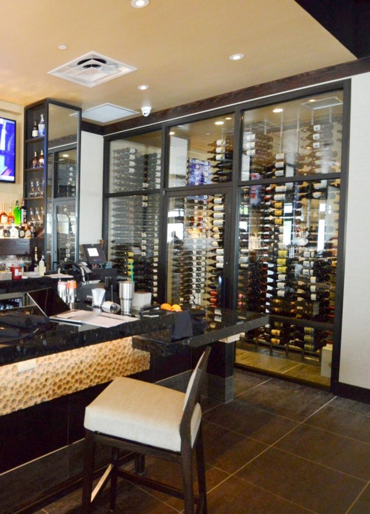 This contemporary commercial custom wine cellar in Denver, Colorado, displays the wines in metal wine racks.